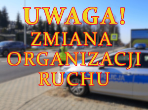 napis Uwaga zmiana organizacji ruchu, w tle policjantka przy radiowozie w rejonie cmentarza