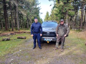 teren leśny, policjant i strażnik leśny przy pojeździe Straży Leśnej