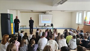dzielnicowy i strażnik miejski rozmawiają z młodzieżą o cyberprzemocy