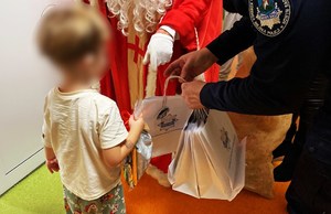 policjant wraz ze św. Mikołajem wręcza prezent małemu chłopcu