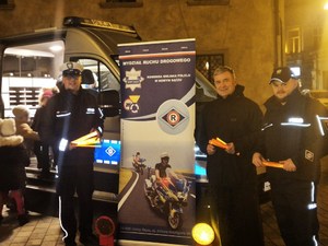 policjanci, ks. proboszcz, w rękach trzymają elementy odblaskowe