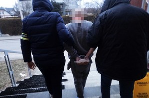 nieumundurowani policjanci prowadzą zatrzymanego mężczyznę