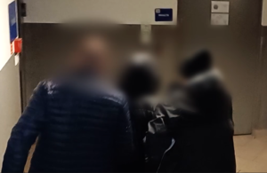 nieumundurowani policjanci prowadzą zatrzymanego mężczyznę