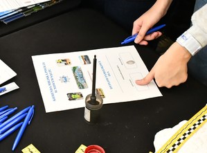 dłoń odbijająca linie papilarne kciuka na dyplomie położonym na stole