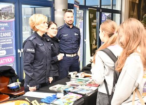 policjanci przy stanowisku profilaktycznym wraz z osobami zainteresowanymi
