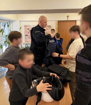 policjant prezentuje uczestnikom spotkania sprzęt służbowy