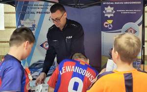 Policjant i uczestnicy balu integracyjnego na stoisku profilaktycznym