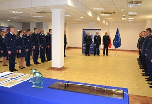 uczestnicy uroczystości, na pierwszym planie stolik na którym znajduje się szabla, pamiątkowe statuetki i podziękowania