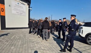 funkcjonariuszka i funkcjonariusze przy budynku stadionu, obok kibice