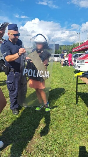 Piotr Kiliański podczas festynu prezentuje chłopcu policyjny sprzęt służbowy