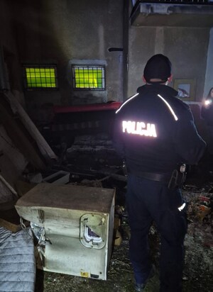 funkcjonariusz sprawdza teren, na drugim planie pracownica MOPS z latarką