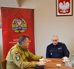 od lewej Komendant Miejski PSP w N. Sączu, Komendant Miejski Policji w N. Sączu, w tle baner PSP i godło