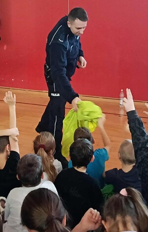 dzielnicowy przekazuje dzieciom kamizelkę odblaskową podczas prelekcję - fot. SP w Piwnicznej-Zdroju