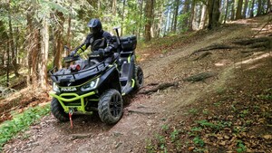 dzielnicowy porusza się quadem w terenie leśnym