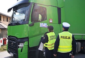 funkcjonariuszka SOK wręcza kierowcy samochodu ciężarowego materiały edukacyjne, obok policjant WRD