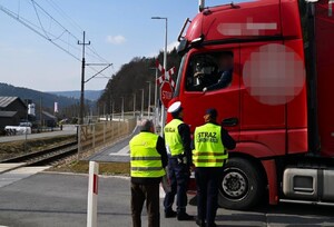 policjant, funkcjonariuszka SOK, przedstawiciel PKP rozmawiają z kierowcą ciężarówki