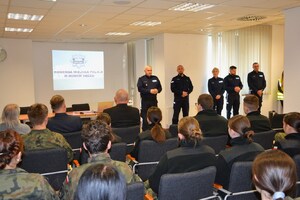 komendant, obok Naczelnik Wydziału Prewencji i inni funkcjonariusze oraz uczniowie w sali konferencyjnej