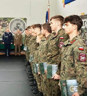 absolwenci stoją w rzędzie, na drugim planie insp. A. Bukański