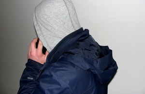 mężczyzna w bluzie w kapturem na głowie rozmawia przez telefon komórkowy
