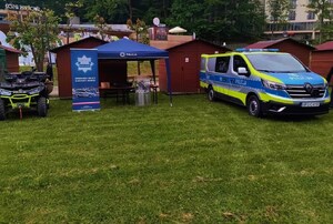 stoisko profilaktyczno-edukacyjne krynickich policjantów, obok pojazdy służbowe