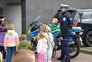 chłopiec siedzi na policyjnym motocyklu, obok policjant ruchu drogowego