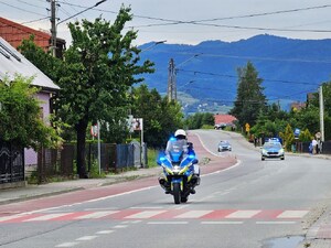 policjant na motocyklu, za nim oznakowane radiowozy