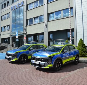 dwa nowe radiowozy przed budynkiem komendy