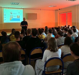dzielnicowy z grupą uczniów uczestniczących w prelekcji