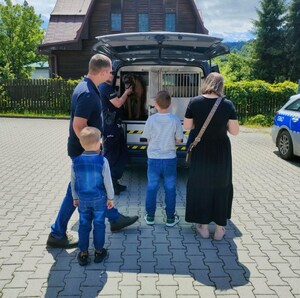 chłopcy wraz z rodzicami przyglądają się psu służbowemu