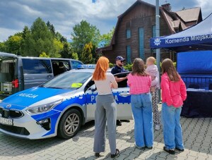 osoby przyglądają się policyjnemu radiowozowi