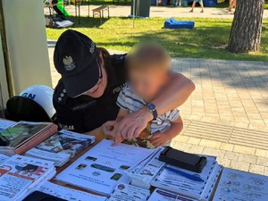 policjantka pomaga odbić chłopcu jego linie papilarne na pamiątkowym dyplomie