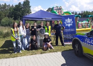 wspólne zdjęcie dzielnicowego i młodzieży ubranej w elementy umundurowania służbowego