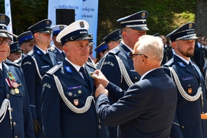32. Przedstawiciel PCK dekoruje policjanta medalem