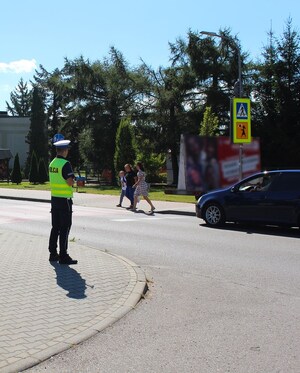 rejon przejścia dla pieszych przy szkole,  policjant, piesi przechodzący na drugą stronę jezdni - fot. arch. KMP NS