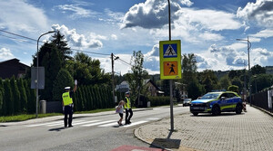 funkcjonariuszka przeprowadza uczennicę przez przejście dla pieszych