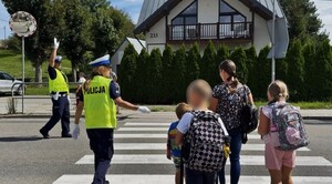 policjantka przeprowadza uczniów przez przejście dla pieszych