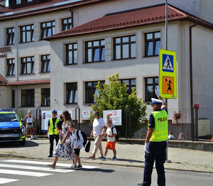 rejon szkoły, uczniowie przechodzą przez przejście dla pieszych, obok policjanci