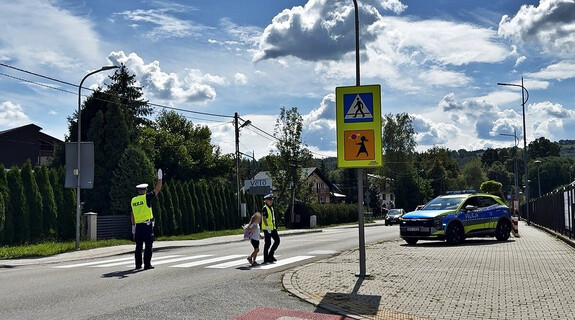 funkcjonariuszka przeprowadza uczennicę przez przejście dla pieszych