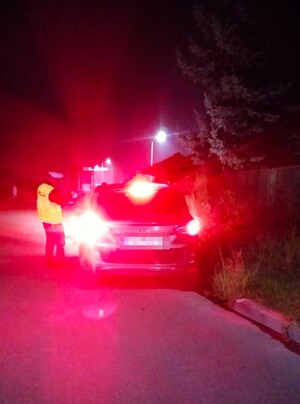 noc, policjant kontroluje samochód osobowy