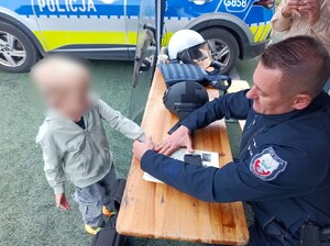 policjant pomaga odbić chłopcu linie papilarne na pamiątkowym dyplomie