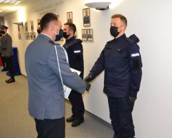 Komendant gratuluje i ściska dłoń pierwszemu z nowych policjantów