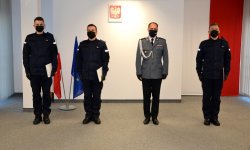 wspólne zdjęcie Komendanta i nowych policjantów na tle godła oraz flagi Polski i UE