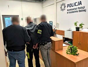 policjanci prowadzą zatrzymanego mężczyznę
