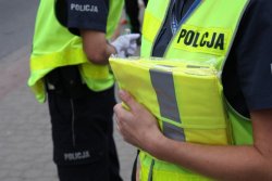 akcja rozdawania odblasków - policjantka trzyma w ręku kamizelki odblaskowe