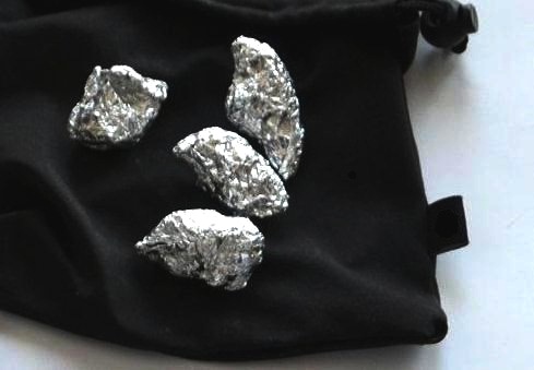 cztery zwitki z folii aluminiowej na czarnej torbie - fotografia ilustracyjna