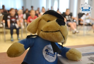 pluszowy piesek, maskotka sądeckiej Policji, w tle dzieci