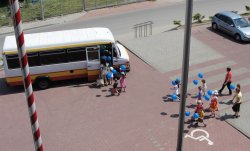 dzieci z balonikami idące do busa zaparkowanego przed komendą