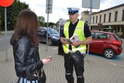 policjant drogówki rozmawia z dziewczyną trzymającą w ręce telefon komórkowy