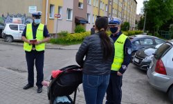 policjanci rozmawiają z kobietą, która prowadzi wózek z małym dzieckiem