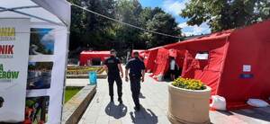 policjant i strażnik miejski patrolują okolice plenerowego punktu szczepień